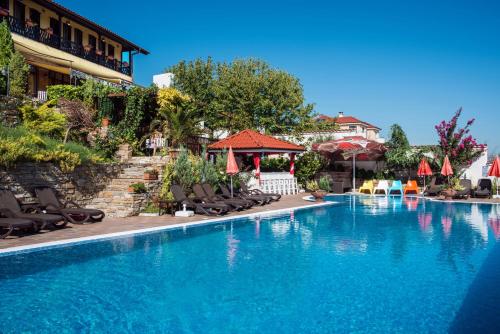 a swimming pool with chairs and umbrellas next to a building at Chiflika Family Hotel in Asenovgrad