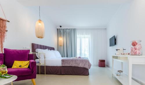 a hotel room with a bed and a purple chair at Comfort Rooms by MaliaMare Hotel in Malia