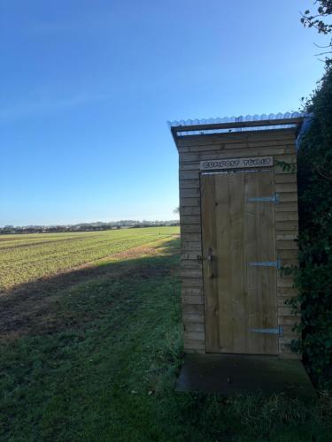 a wooden outhouse with a door in a field at Pear Tree Hut at Carr house farm in Scarborough