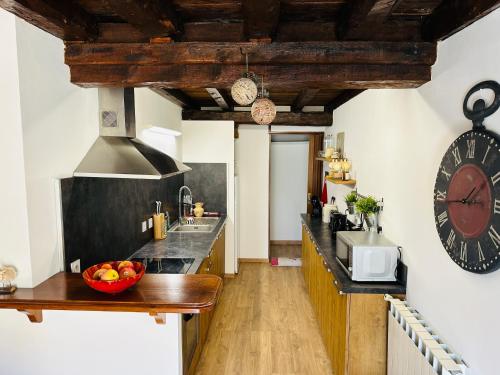une cuisine avec un comptoir et une horloge au mur dans l'établissement Maison au coeur des Angles, aux Angles