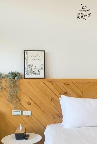 a bedroom with a bed with a wooden head board at Still Hills Inn in Hengchun