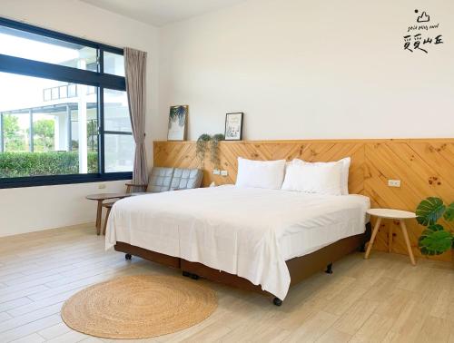 a bedroom with a large bed and a large window at Still Hills Inn in Hengchun