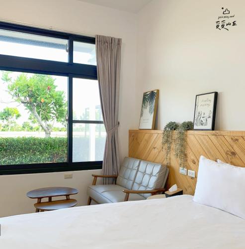 a bedroom with a bed and a chair and a window at Still Hills Inn in Hengchun