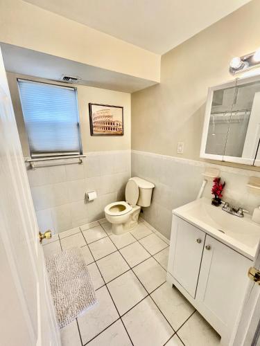 a white bathroom with a toilet and a sink at 4 bedroom apt in Newark in Newark