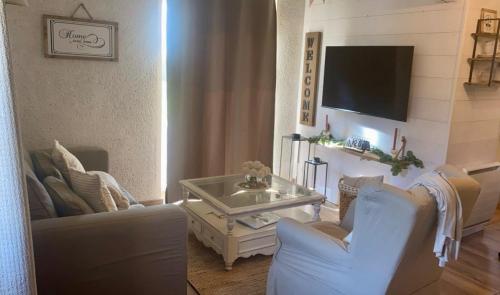 un salon avec deux chaises et une télévision dans l'établissement L'écrin, charmant cottage aux portes de la cité médiévale de Semur-en-Auxois, à Chevigny