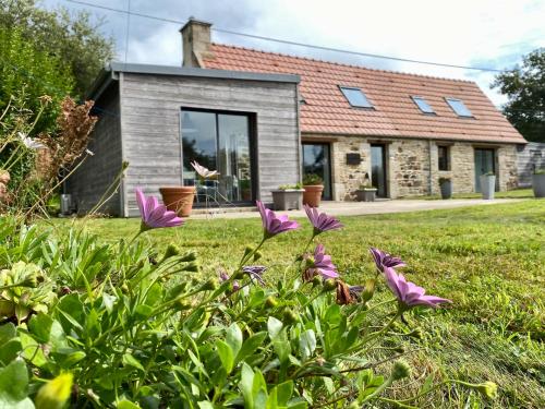 une maison avec des fleurs violettes dans la cour dans l'établissement Le Penn Ty, à Trébeurden