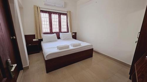 a small bed in a room with a window at Chippy Apartments No 56 in Chennai