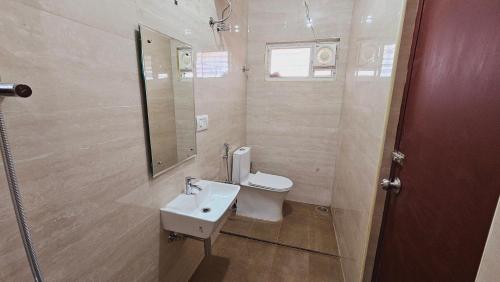 a bathroom with a toilet and a sink and a mirror at Chippy Apartments No 56 in Chennai