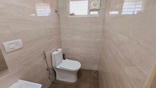 a small bathroom with a toilet and a window at Chippy Apartments No 56 in Chennai