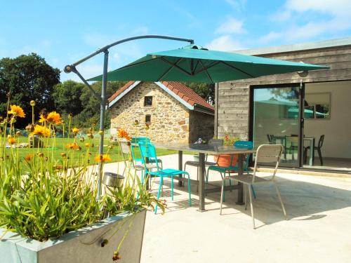 - une table avec des chaises et un parasol dans le jardin dans l'établissement Le Penn Ty, à Trébeurden
