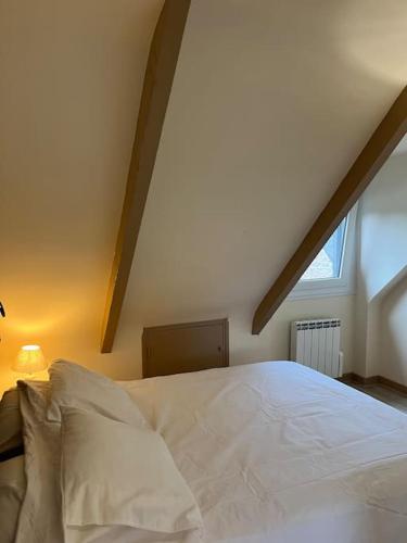 une chambre avec un lit blanc dans un grenier dans l'établissement La Voûte, à Kerfot
