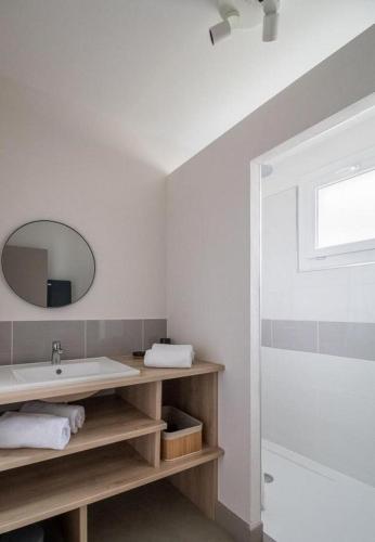 une salle de bain blanche avec un lavabo et un miroir dans l'établissement Gites 4 et 6 personnes au cœur du centre médiéval de Billom, à Billom