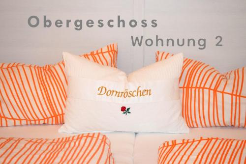 a bed with orange and white pillows with the words undone at Ferienwohnungen Dornröschen in Weißensberg