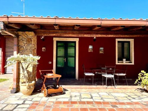 a red house with a patio with a table and chairs at Case Di Loco Castro in Agnone Bagni