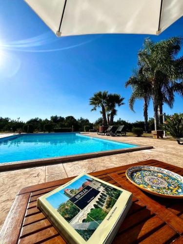 a book on a table next to a swimming pool at Case Di Loco Castro in Agnone Bagni