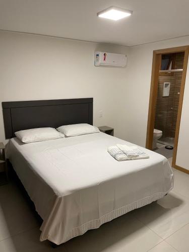 a bedroom with a large bed with white sheets at Apt Tranquilo na Praia do Forte in Praia do Forte