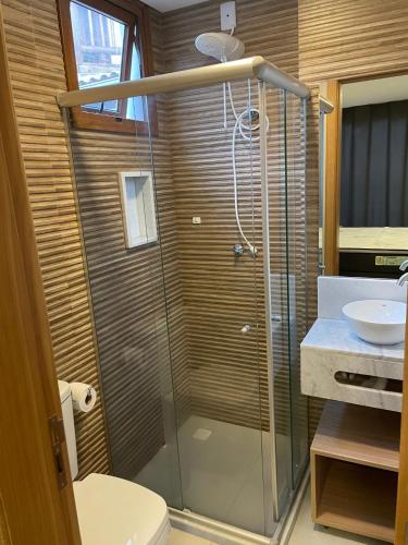 a bathroom with a shower with a toilet and a sink at Apt Tranquilo na Praia do Forte in Praia do Forte