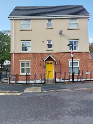 a house with a yellow door and a fence at Double room in Walsall in Bloxwich