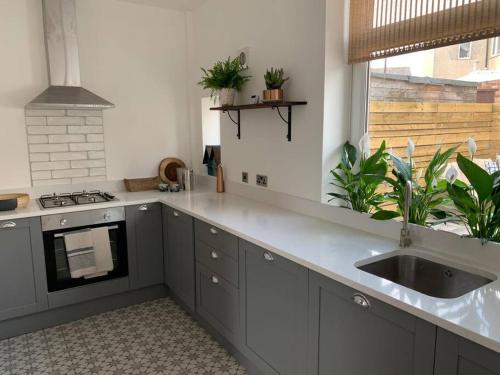 a kitchen with gray cabinets and a sink and a window at Harebell Cottage in Wylam Village Sleeps 4 in Wylam