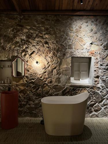 a bathroom with a tub and a stone wall at ShuShu Homestay in Jiufen