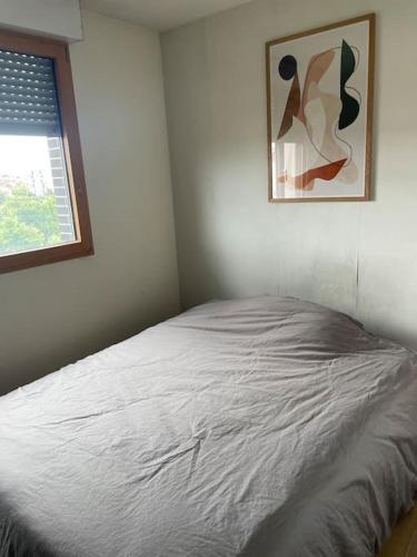 un lit dans une chambre avec un tableau sur le mur dans l'établissement Superbe deux pièces avec terrasse proche du métro, à Montreuil