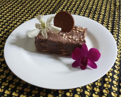 a piece of chocolate cake on a white plate with a purple flower at Dishari Tangalle in Tangalle