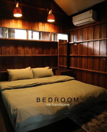 a bedroom with a bed in a room with wooden walls at mrhandsome phayao in Ban Mae Ka Hua Thung