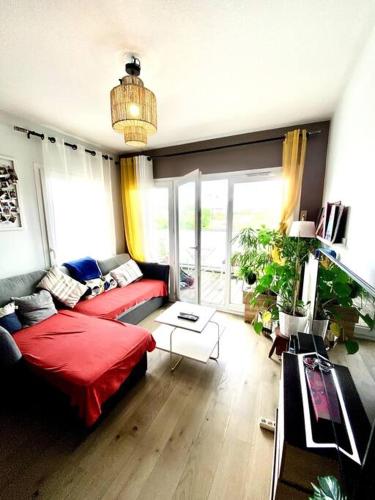 - un salon avec un canapé rouge et une grande fenêtre dans l'établissement Appartement cosy - balcon - parking gratuit - 10min centre ville, à Cenon