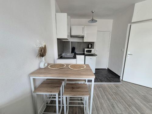 une petite cuisine avec une table et des chaises en bois dans l'établissement Le Cocon-T2-Proche du centre-Wifi, à Lourdes