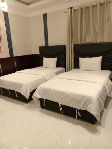 two beds sitting next to each other in a room at AAA Hotel Apartments in Al Duwika