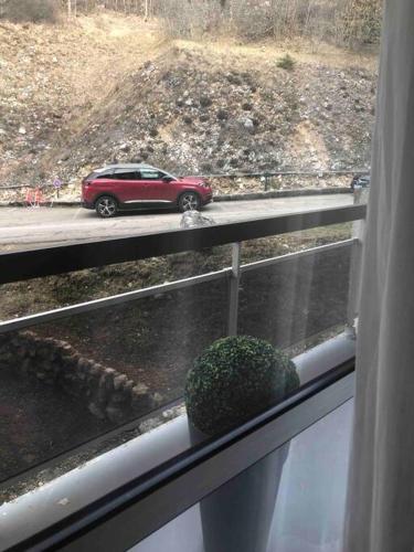 Une voiture rouge sur une route sous la pluie depuis une fenêtre dans l'établissement Appartement lumineux 2 ch, à Villard-de-Lans