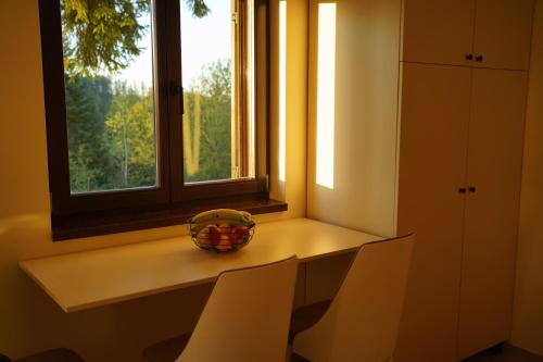 a table with chairs and a bowl of fruit on a window at Star Hill Apartments in Nova Varoš