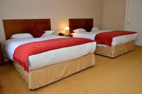 a hotel room with two beds with red and white sheets at Cooneys Hotel in Ballymahon