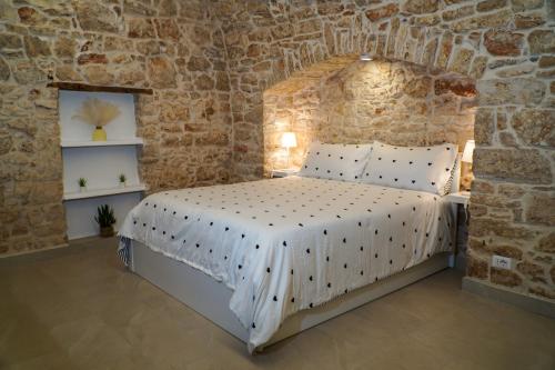 a bedroom with a bed in a stone wall at Dimora di Sasso - Relax ed Eleganza nel Cuore della Puglia in Santeramo in Colle