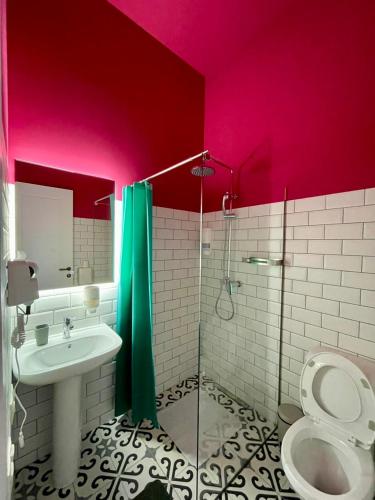 a bathroom with a toilet and a sink and pink walls at Communa Good Vibes in Tbilisi City