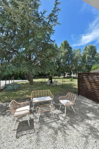 un groupe de trois chaises et une table dans une cour dans l'établissement Appartement 4 personnes entrée le Touquet avec terrasse et jardin, à Cucq
