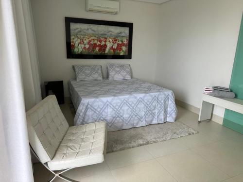 a bedroom with a bed and a chair in it at Loft excelente no centro de Governador Valadares in Governador Valadares