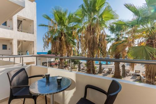 a balcony with a table and chairs and palm trees at Gouves Bay by Omilos Hotels in Gouves