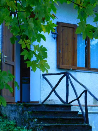 a building with wooden windows and stairs in front at Graziosa Casetta Con Camino In Pietra e Giardino in Abetone