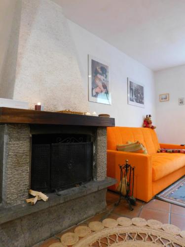 a living room with an orange couch and a fireplace at Graziosa Casetta Con Camino In Pietra e Giardino in Abetone