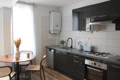 une cuisine avec des armoires noires et une petite table dans l'établissement L'escapade, entièrement rénové, proche centre, à Grenoble