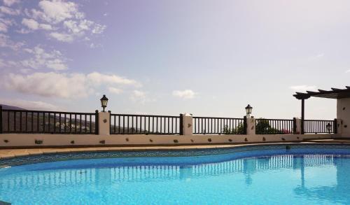 a large swimming pool next to a fence at Villa Altos de Santiago in Playa de Santiago