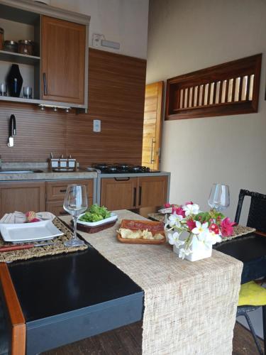 a kitchen with a table with food and wine glasses at Bangalô Exclusivo Pontal do Maceió in Maceio