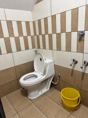 a bathroom with a toilet and a yellow bucket at COCHIN HOMES in Cochin