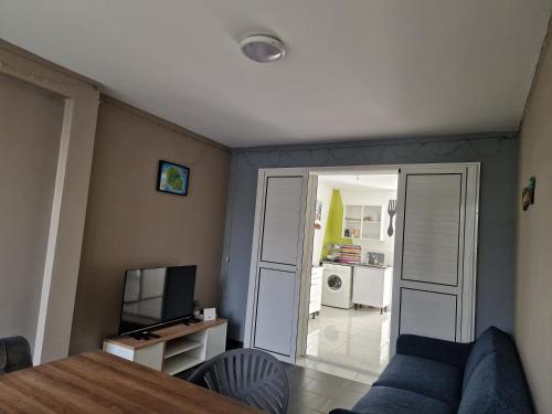 a living room with a blue couch and a television at Dodo La FaMi in Sainte-Suzanne