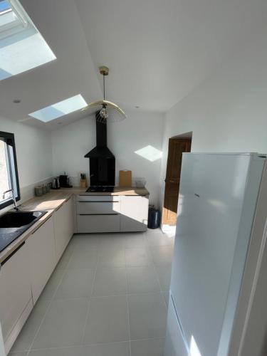  La cuisine est équipée de placards blancs et d'un réfrigérateur. dans l'établissement Maison de campagne, à Hautefage