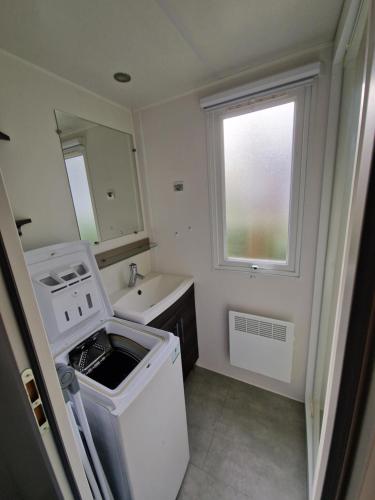 Elle comprend une petite salle de bains pourvue d'un lavabo et d'un lave-linge. dans l'établissement Mobile home 210 Siblu La Pignade Fun pass non inclus, à La Tremblade