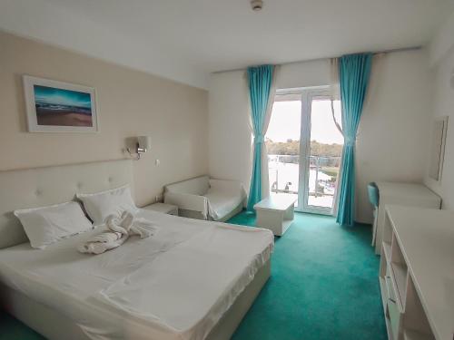 a bedroom with a large white bed and a window at Blooming by the Sea - camere cu vedere frontală spre mare in Olimp