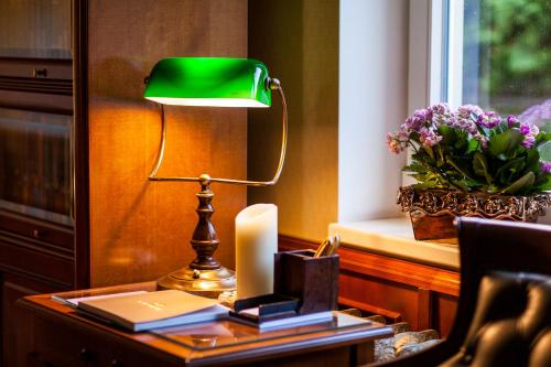 a green lamp on a table with a candle and books at TB Palace Hotel & SPA in Jūrmala