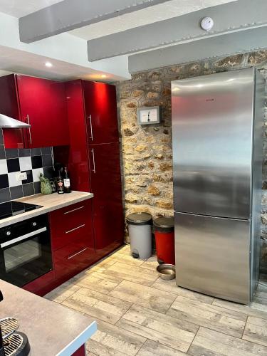 La cuisine est équipée de placards rouges et d'un réfrigérateur en acier inoxydable. dans l'établissement Gite Les Petits Dragons, à Carnoët